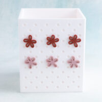 White pen holder snappy pot with small pink and red flower charm on charms