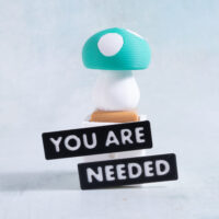 Green and white mushroom clicker fidget on a Snappy Pots planter with you are needed word charms